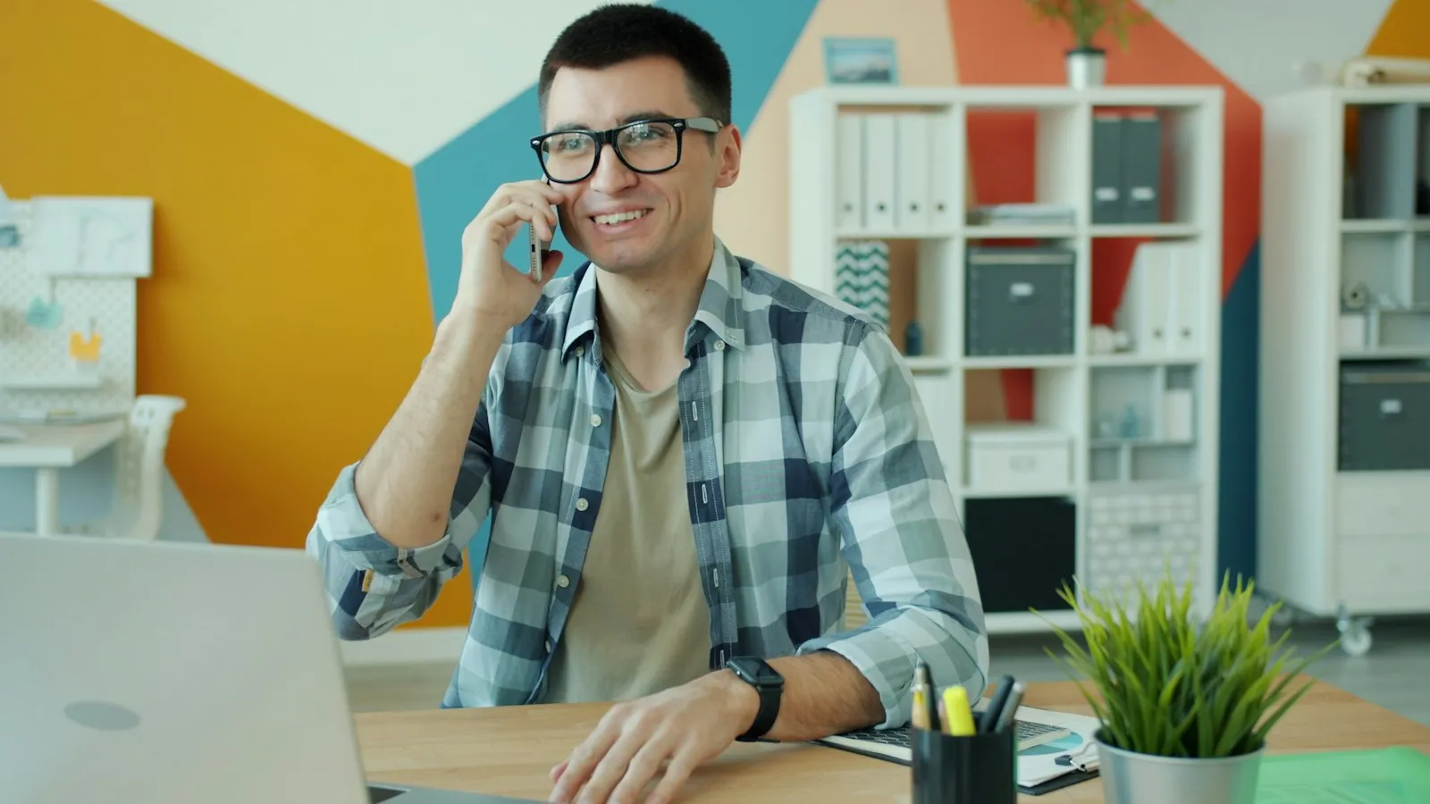 Profissional sorrindo ao telefone em frente ao notebook