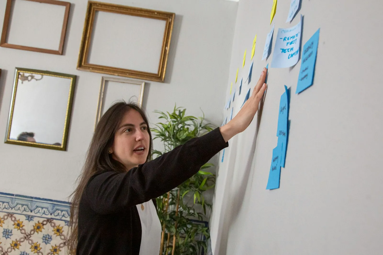 Mulher colando post-its em uma parede para mapear a jornada de usuários