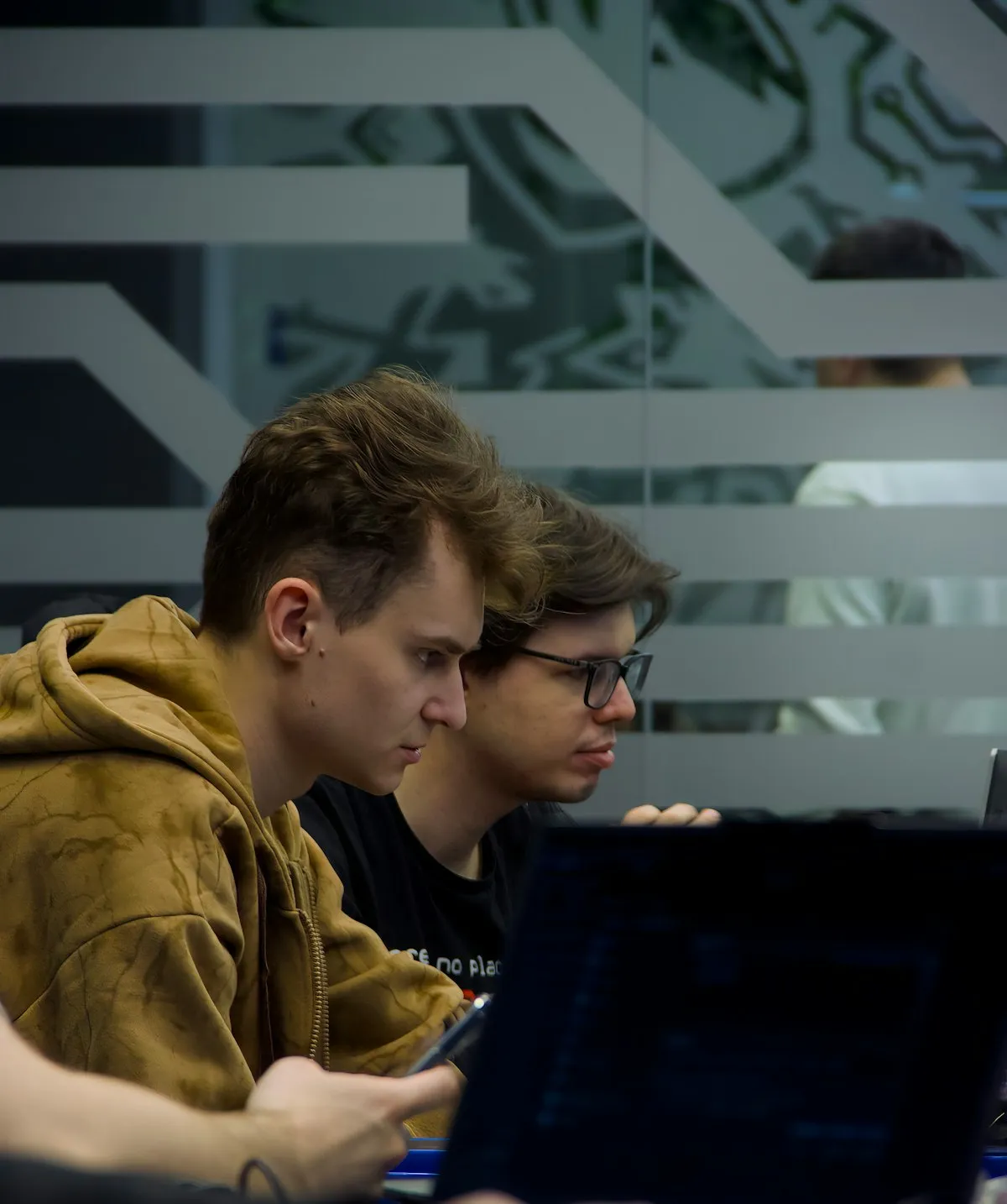 Dois desenvolvedores lado a lado, concentrados na tela de um notebook