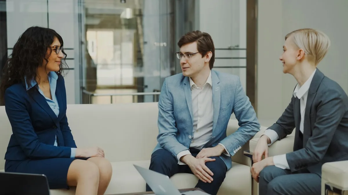 Três profissionais conversando em um sofá, em uma reunião de trabalho.